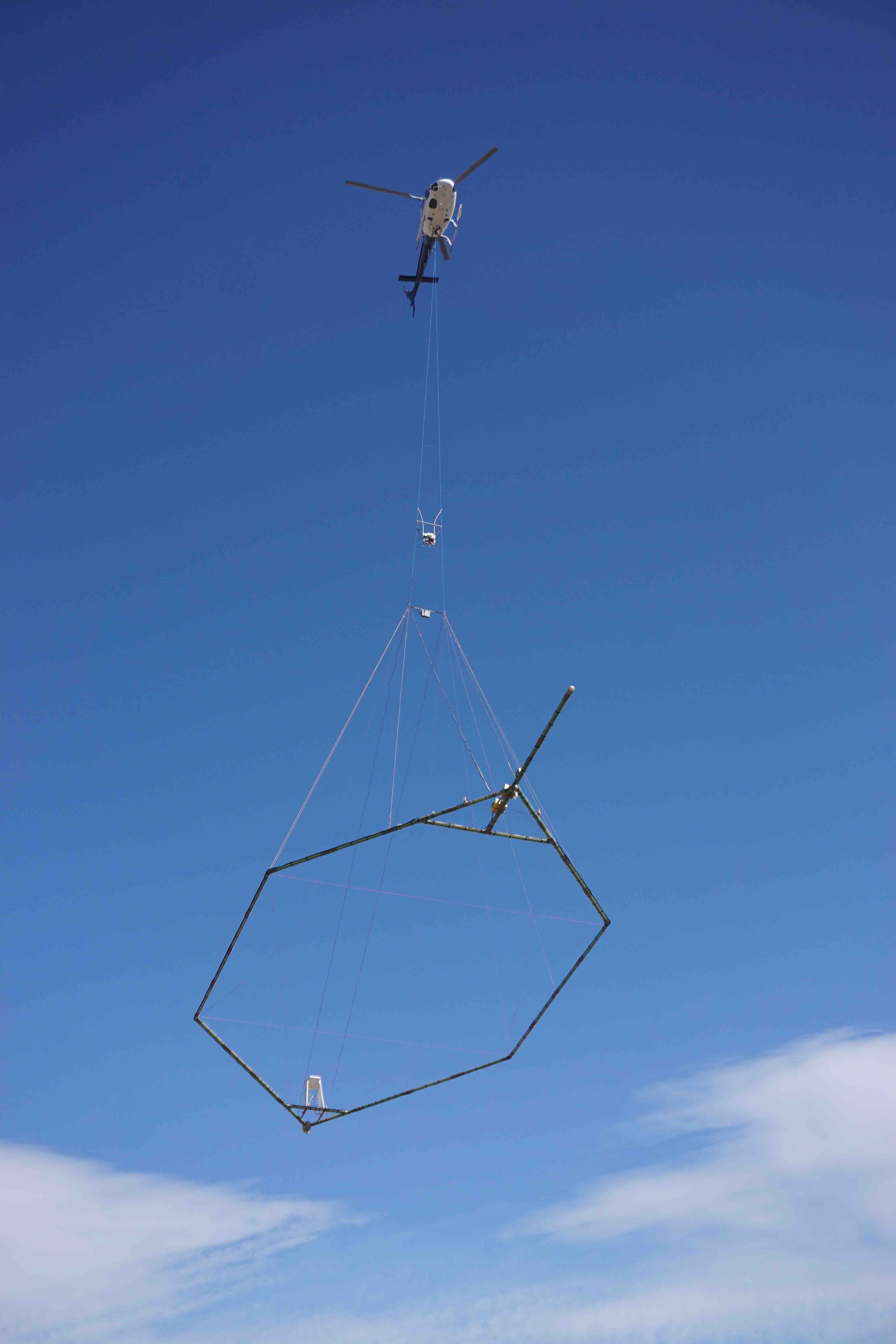 A helicopter carrying a large hexigon array used by SkyTEM.